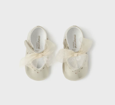 Pair of white sandals with bow details on a light gray background