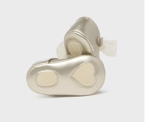 Pair of gold baby shoes on a light gray background