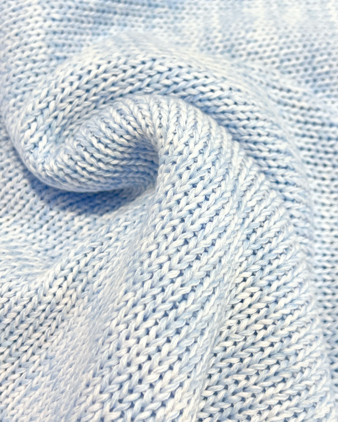 Close-up of light blue knitted fabric with a textured pattern.