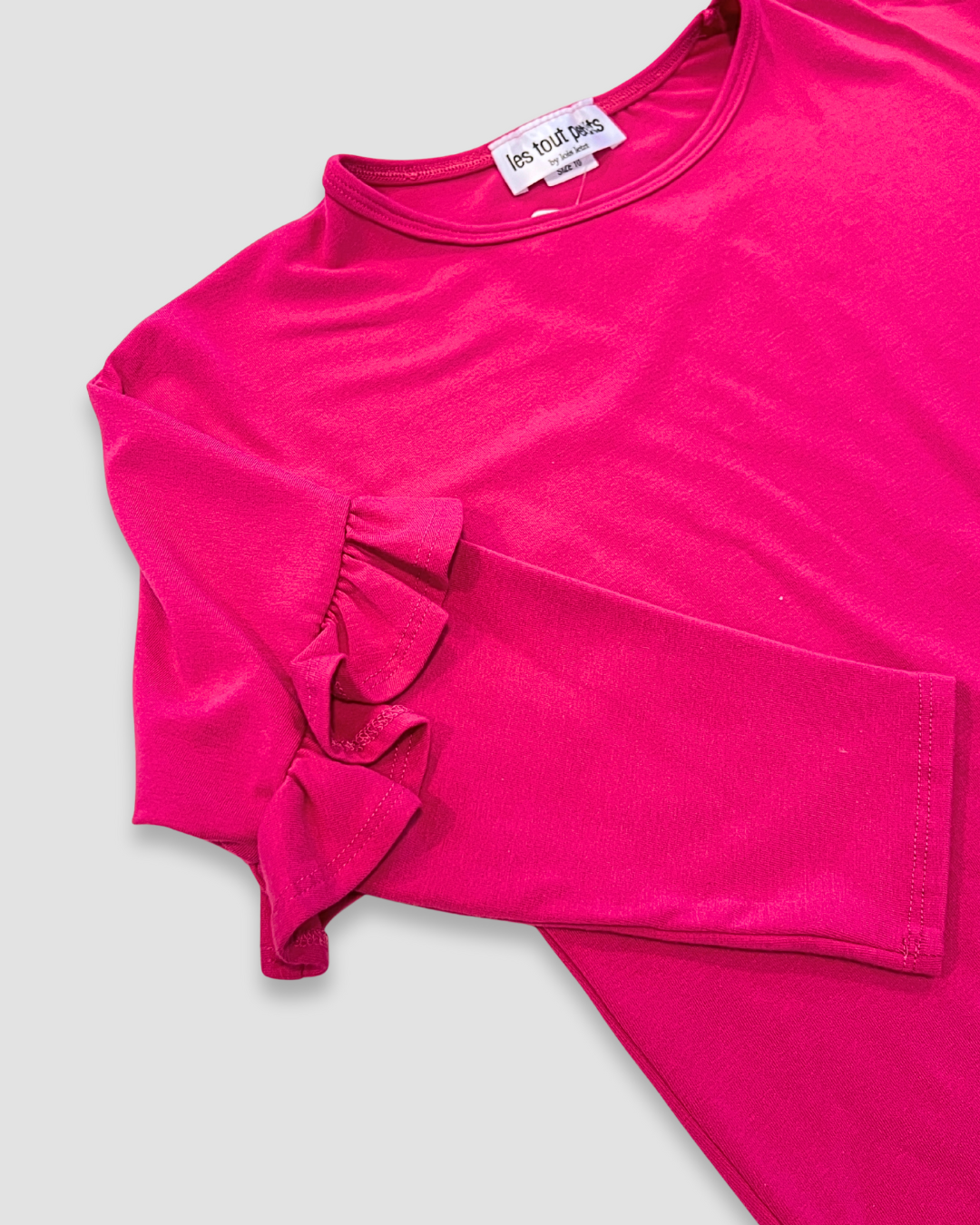 Pink ruffled shirt on a light gray background